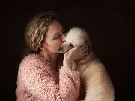 curly girl and poodle. A dog similar to its people. portrait in studio. attitude, love, understanding with petの写真素材
