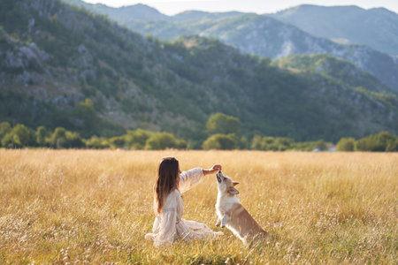 A woman joyfully spins outdoors holding her Welsh Corgiの写真素材