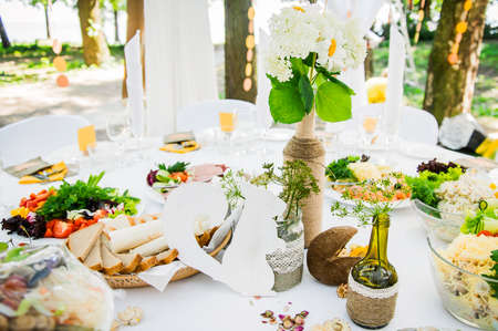 Decoration of the festive table with flowers, greenery and wooden figures. Accessories made of natural materials for restaurant serviceの写真素材