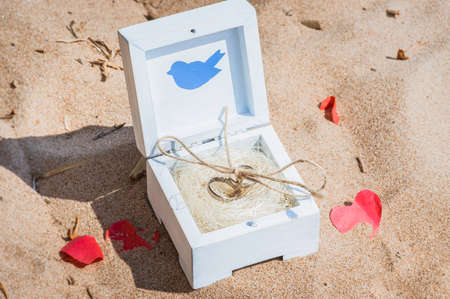 Two wedding rings in a wooden handmade box on the sand. Wedding decoration in rustic style