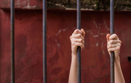 The girl's hands are held by metal bars. Symbol of violation of women's rights. Background