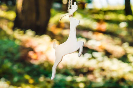 A wooden figure of a deer is suspended from a tree. Accessories, toys and decor handmade in rustic styleの写真素材