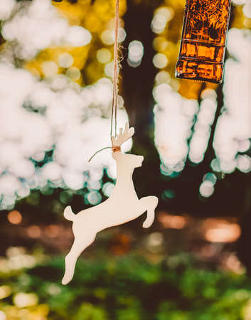 A wooden figure of a deer and a glass are suspended from a tree. Accessories, toys and decor...