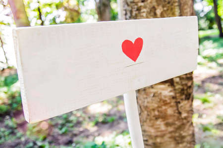 A wooden white signboard with a heart drawn on it. Decoration of the holiday in the open air in the rustic styleの写真素材