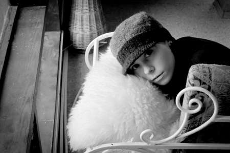 a girl in hat lying on a forged couch on sheepskin