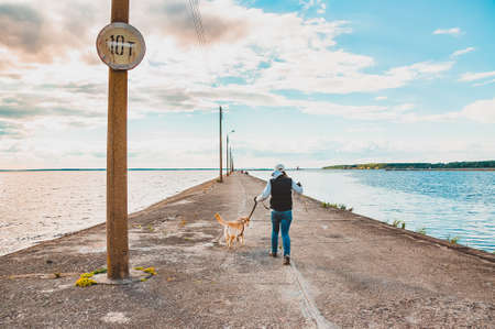 Labrador Retriever and a girl run along the pier. Traveling with a dog to the sea
