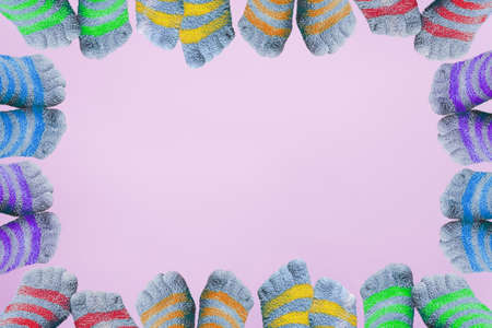 twelve pairs of legs in striped socks with separate fingers in colors of LGBT flag form the frame on pink backgroundの写真素材