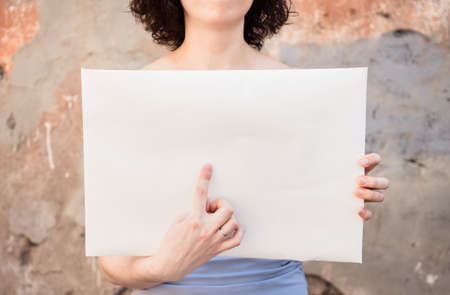 The girl is holding an empty poster. Women's Single picket on the background of a wall on the street.の写真素材