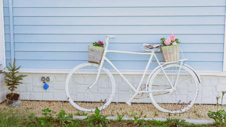 Retro Bicycle with two baskets of flowers on the background of a blue house. Garden decor in Provence styleの写真素材