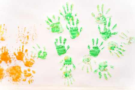 a sheet of paper with green and orange prints of children's handsの写真素材
