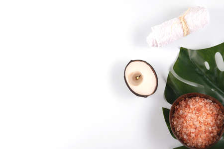 Scented sea salt and white face towel with the coconut candle for relaxed mood on the green leaf.の写真素材