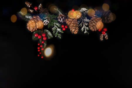 Golden garland, forest pinecones, red berries and green leaves in snow on the black background with...