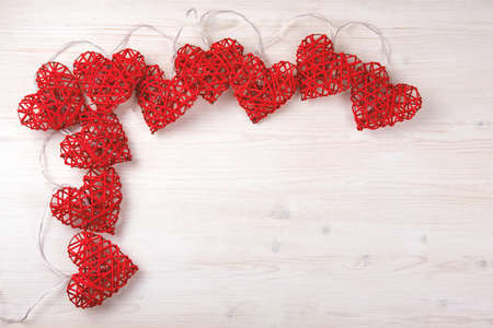 Red lights in shape of beautiful hearts on light wood background. St Valentines concept with copy...