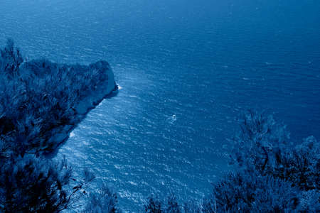 Beautiful seascape from above of a rock with a ship in the trendy classic blue color of the year.