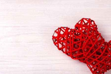 Two beautiful wicker red hearts on the light wood background. St Valentines concept with copy space.の写真素材