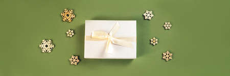 The beautiful new year composition of the present and wooden snowflakes on the green background as a...