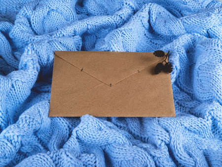 Beautiful brown paper envelope on the cute pale blue wool knitted background.の写真素材
