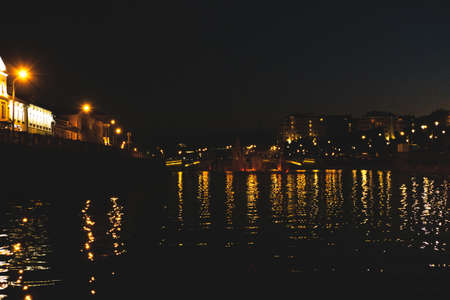 The beautiful view on the city river from the motor boat at night with the reflection of the lights,...