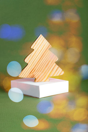 The zero waste new year concept as a handmade wooden fir tree on the white basement against the green background with the sparkles.の写真素材