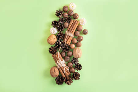 Christmas or New Year natural composition of nuts, cones and cinnamon on the green background. Beige...