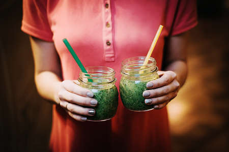 Two green cocktails in hands.