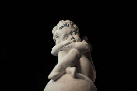 A sad angel sits on a stone. Angel statueの写真素材