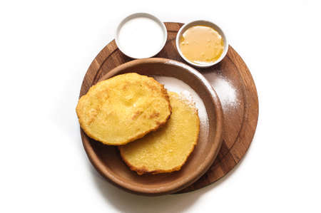 Corn cakes with honey and sour cream on a plate on a white backgroundの写真素材