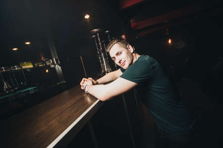 Handsome young man sitting at the counter in the hookah cafeの写真素材