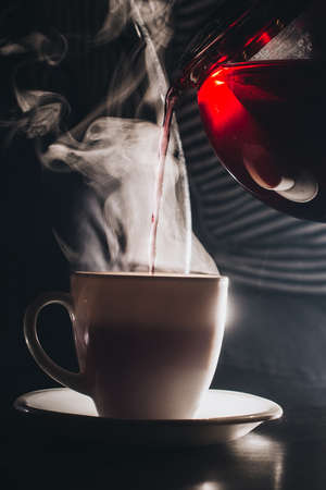 Girl 20 years old pours black tea from glass kettle to cup in hookah cafe closeupの写真素材