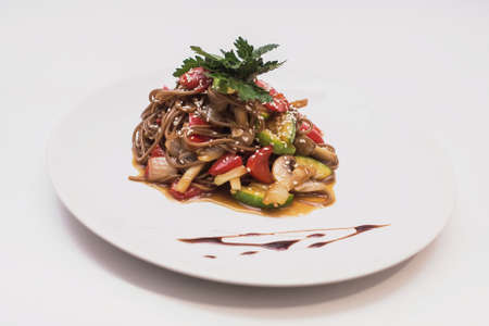 Buckwheat noodles with vegetables and mushrooms in round plate isolated on white backgroundの写真素材