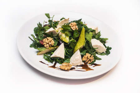 Salad with pears with cheese and walnuts on a white plate on a white backgroundの写真素材