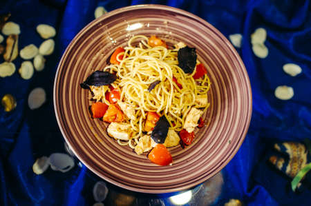 Pasta with chicken and tomatoes on a plateの写真素材