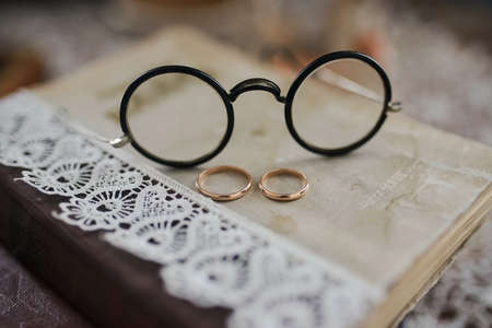Wedding rings on a pile of books with glasses closeの写真素材
