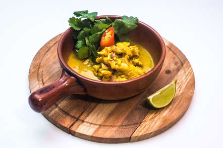 chicken curry with greens in a brown bowl on a board on a white backgroundの写真素材