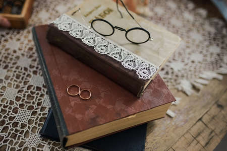 Wedding rings on a pile of books with glassesの写真素材