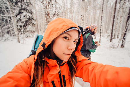 Winter sport activity. Woman hiker hiking with backpack and snowshoes snowshoeing on snow trail...