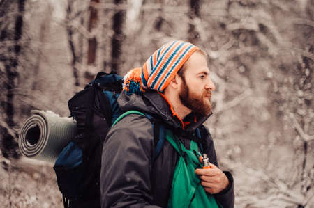 Portrait of smiling bearded man hiker, who relaxing in the winter forest. Toned image. Man with a beard tourist in a winter forestの写真素材