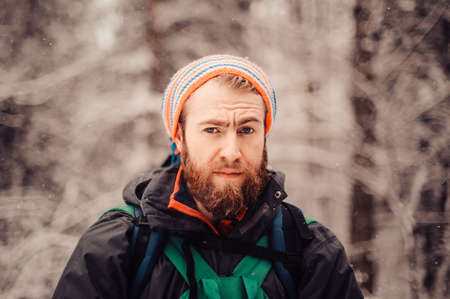 Portrait of smiling bearded man hiker, who relaxing in the winter forest. Toned image. Man with a beard tourist in a winter forest. closeの写真素材