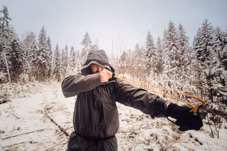 Portrait of smiling bearded man hiker, who relaxing in the winter forest. Toned image. Man with a beard tourist in a winter forest. Walks through the forest. Shoots from a slingshot. one moreの写真素材