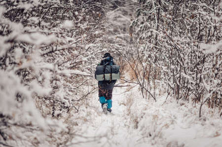 Portrait of smiling bearded man hiker, who relaxing in the winter forest. Toned image. Man with a beard tourist in a winter forest. Walks through the forest. Goes furtherの写真素材
