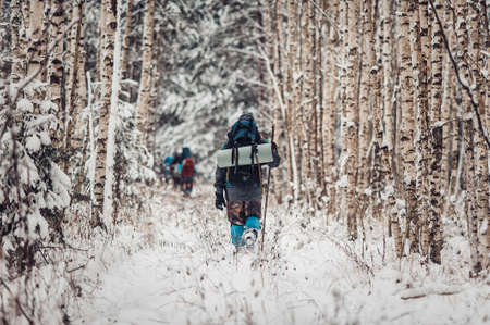 Portrait of smiling bearded man hiker, who relaxing in the winter forest. Toned image. Man with a beard tourist in a winter forest. Walks through the forest. Goes further in the forestの写真素材