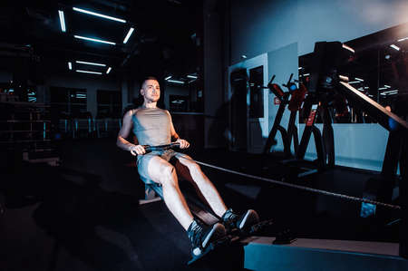 A young man is engaged in a rowing machineの写真素材