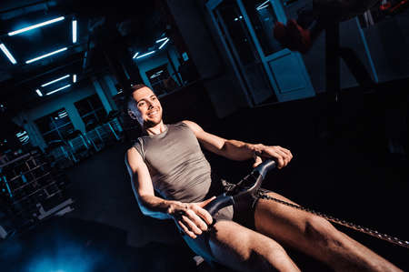 A young man is engaged in a rowing machineの写真素材