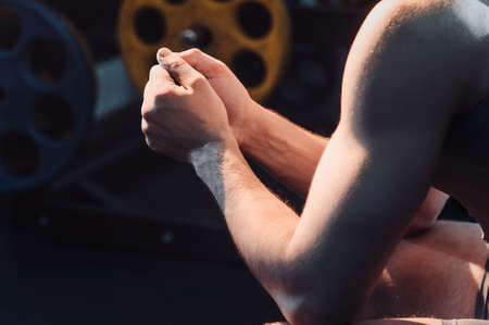 Portrait of bodybuilder muscular sitting posing on a flat bench in dark indoors gym.の写真素材