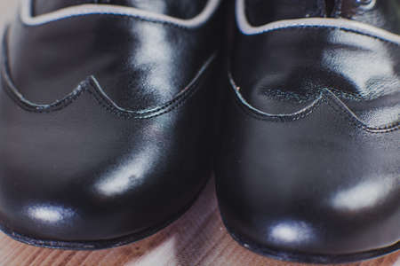 Stylish black with a gray stripe man's crafted shoes for ballroom dancing made of genuine leather on the wooden background. men's black with a gray stripe boots for ballroom dancing. macro view closeの写真素材