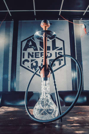 Crafted hand-made hookah stands on a wooden table in a hookah cafe on the background of the art...