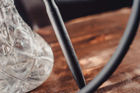 Crafted hand-made hookah stands on a wooden table in a hookah cafe on the background of the art wall. flask of hookah view closeの写真素材