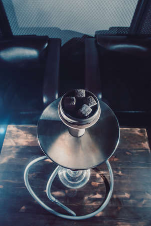 Crafted hand-made hookah stands on a wooden table in a hookah cafe on the background of the art wall. gray hookah view from the topの写真素材