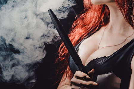 Red-haired sexy girl in a cafe smoking a hookah dressed in black body