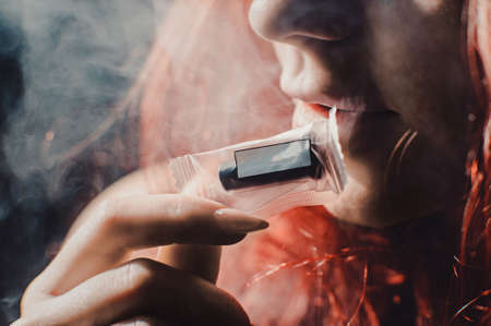 Red-haired sexy girl in a cafe smoking a hookah dressed in black bodyの写真素材